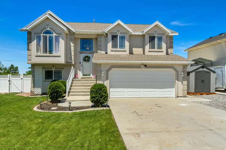 Two-story residence featuring a stucco exterior with decorative trim accents, multiple dormer windows, an arched window, an attached two-car garage, and a concrete driveway