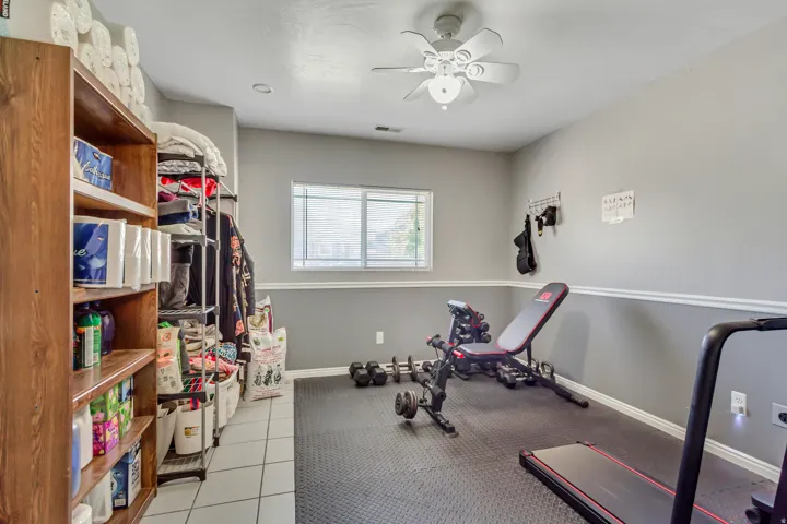 Dedicated room featuring a window, ceiling fan, and two-tone painted walls with chair rail molding