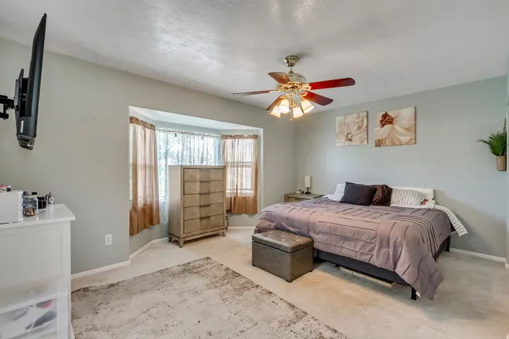 Spacious room featuring a bay window, ceiling fan, and light gray wall paint
