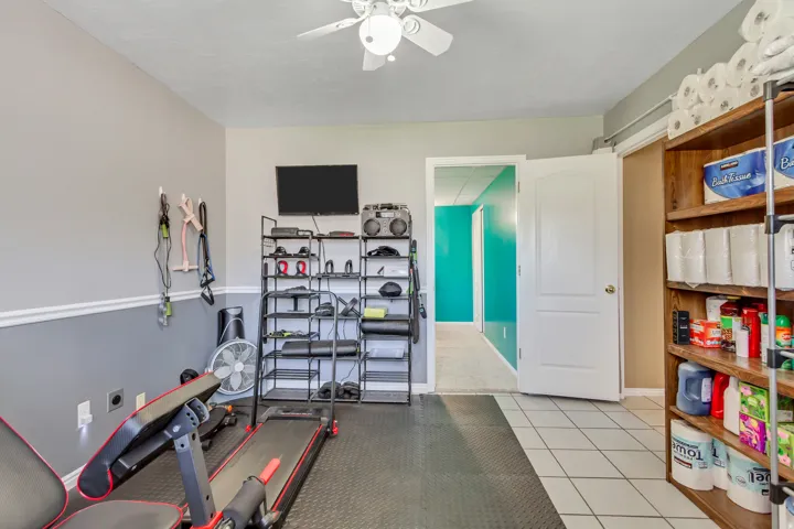 Room featuring a ceiling fan, two-tone wall paint with chair rail molding, and tile flooring