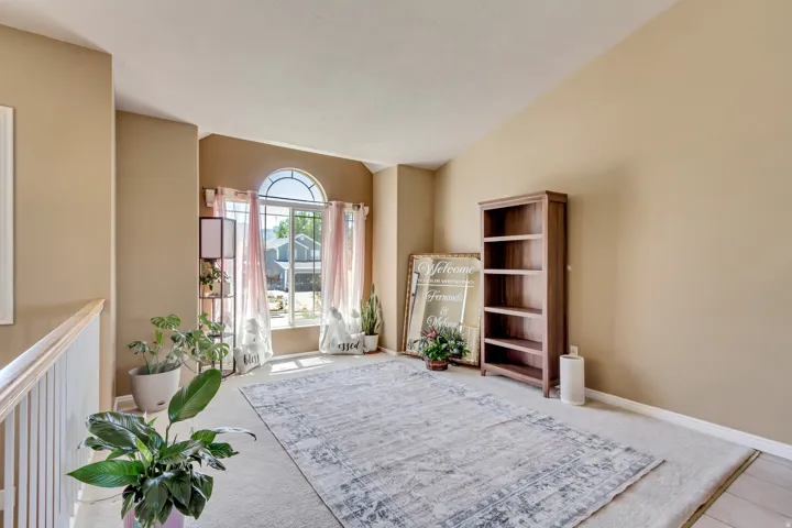 Arched window with upper transom, vaulted ceilings, and light-colored carpeting
