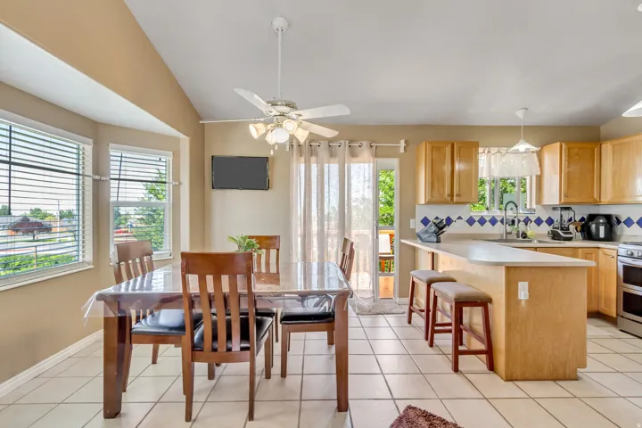 Open-concept kitchen and dining area featuring light wood cabinetry, a breakfast bar, and tile flooring