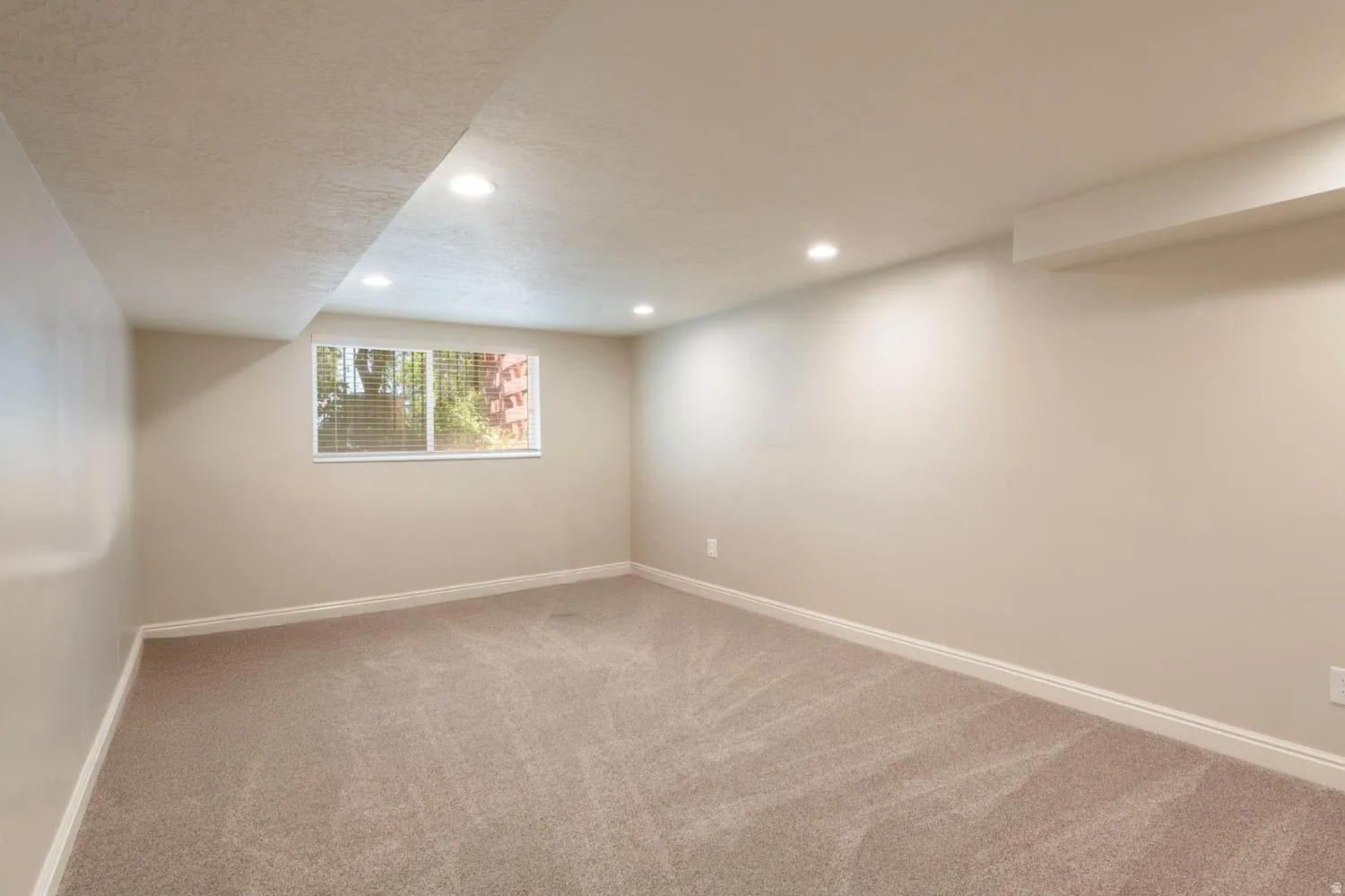 Carpeted room featuring a window with blinds, recessed lighting, and light-colored walls