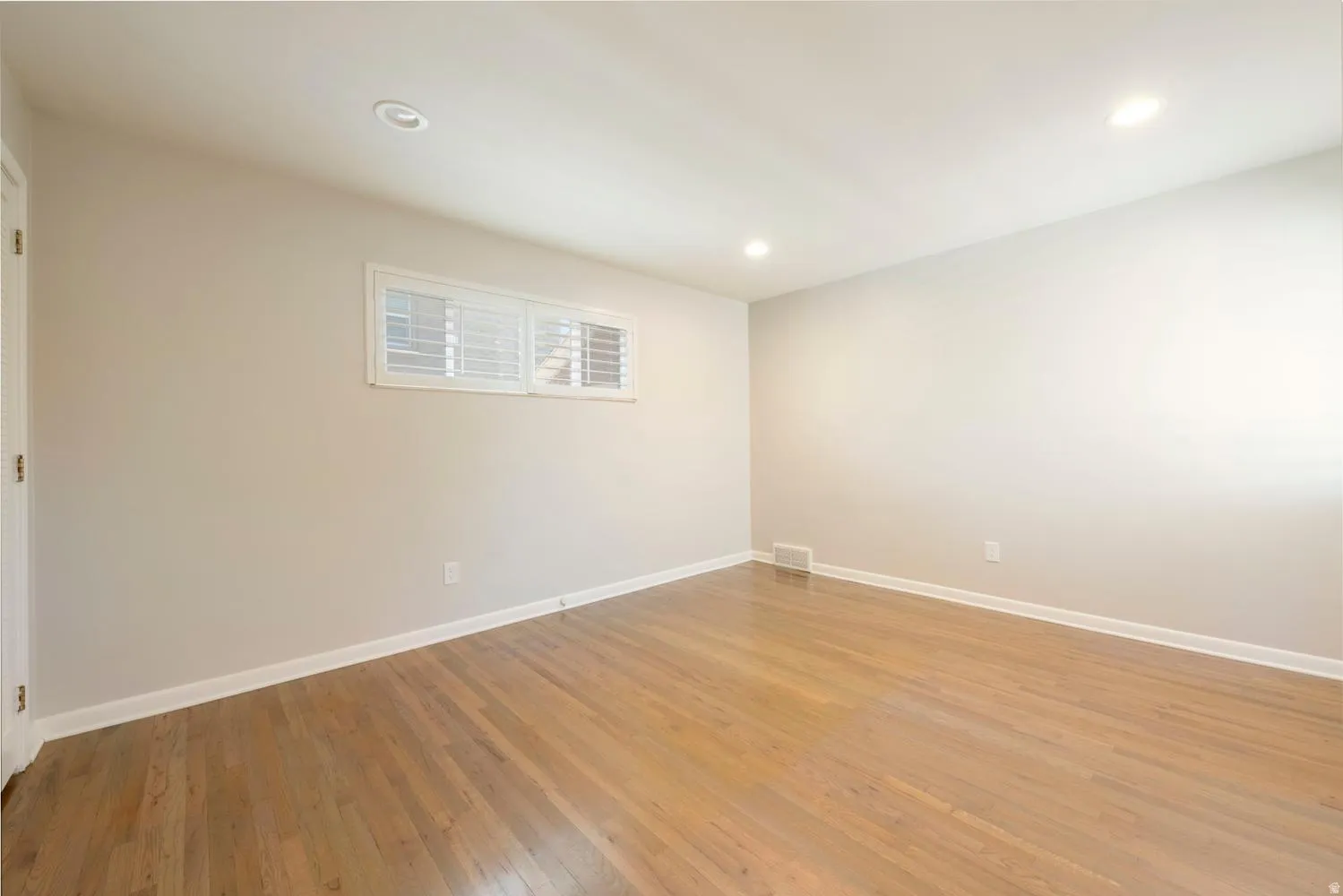 Hardwood flooring, neutral paint palette, recessed lighting, and white baseboards