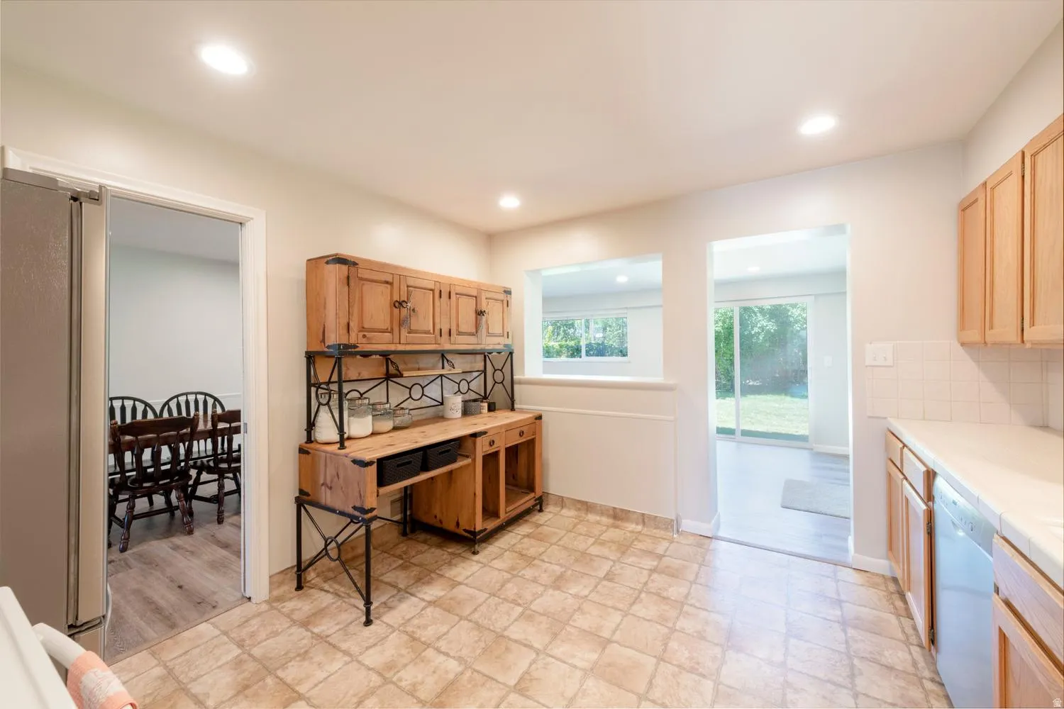 Kitchen featuring recessed lighting, cabinetry, and a pass-through window, access into dining room and family room