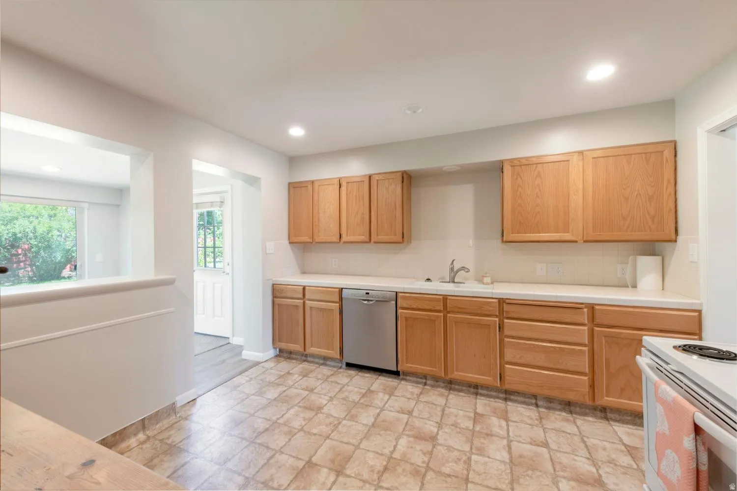 Kitchen featuring cabinetry, light-toned countertops, and a stainless steel dishwasher