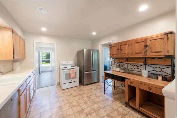 Kitchen featuring cabinetry, stainless steel refrigerator, white electric range, and clean flooring