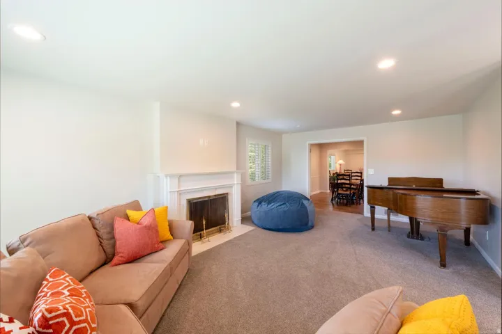 Living area featuring recessed lighting, a fireplace with a white mantel, and neutral-toned carpeting