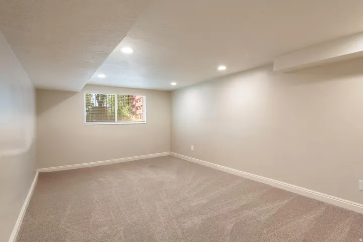 Carpeted room featuring a window with blinds, recessed lighting, and light-colored walls