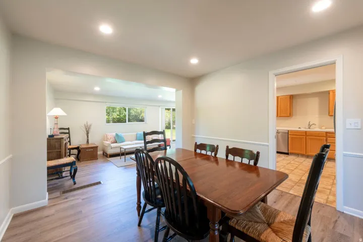 Dining area with newer flooring, recessed lighting, and chair rail molding