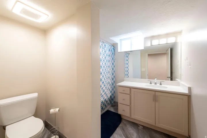 Remodeled bathroom featuring a single vanity with light-colored cabinetry, an integrated sink, a large mirror, and a window above the vanity
