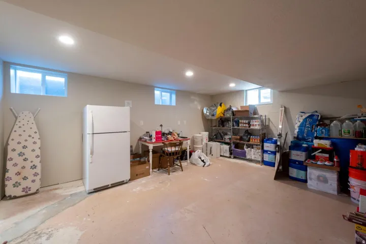 Spacious lower level room featuring light-toned walls, multiple recessed ceiling lights, and several windows, This storage room is plumbed for kitchenette!
