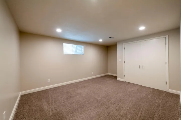 Carpeted room featuring recessed lighting, a window with horizontal blinds, and a built-in double-door closet