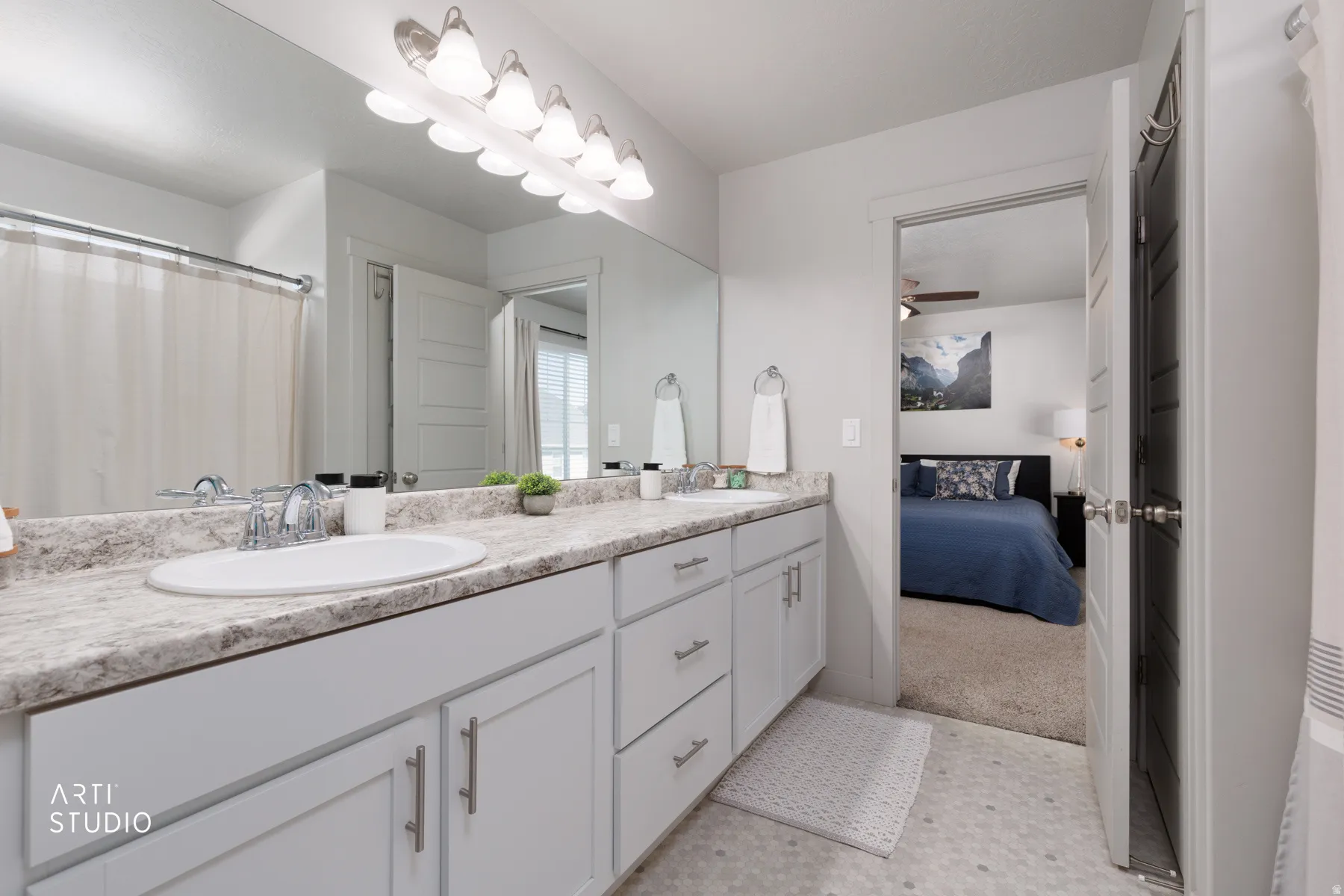 Double vanity with light-toned countertops and undermount sinks, chrome fixtures, and a large wall-mounted mirror