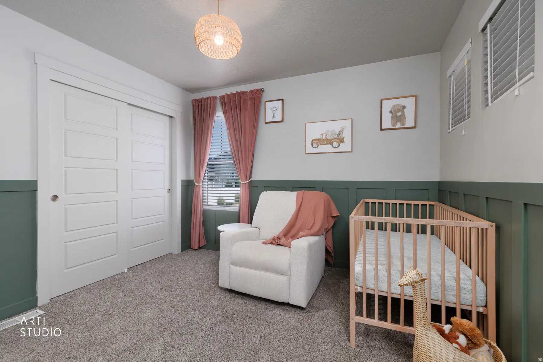 Bedroom featuring a paneled accent wall, neutral carpeting, and a woven pendant light fixture