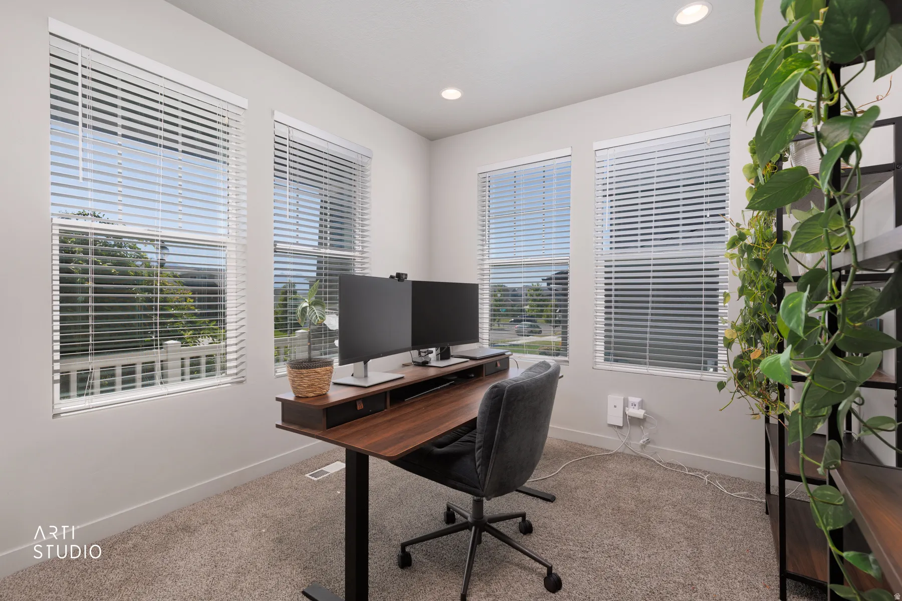 Carpeted room with three large windows featuring white blinds, recessed lighting, and a neutral wall color