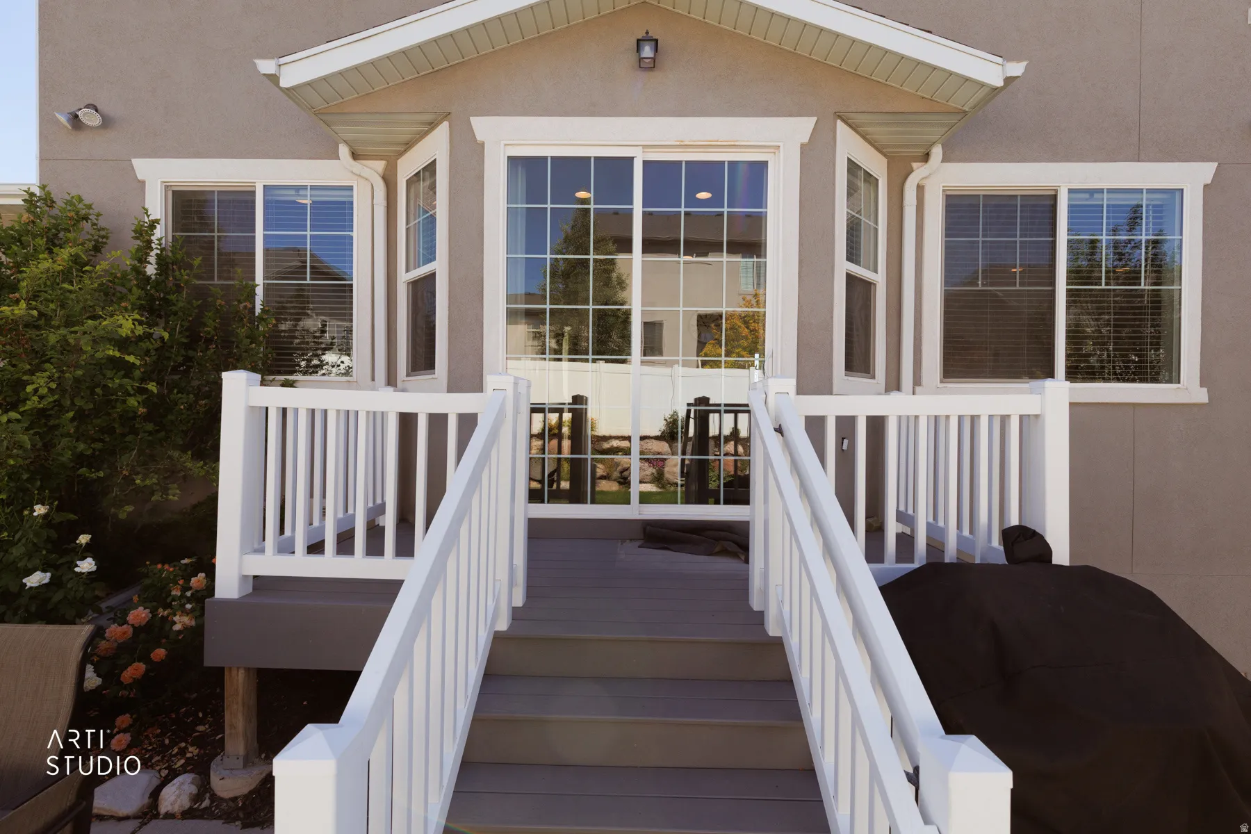 Spacious outdoor deck with railings and steps, offering direct access to the interior through a multi-pane sliding glass door