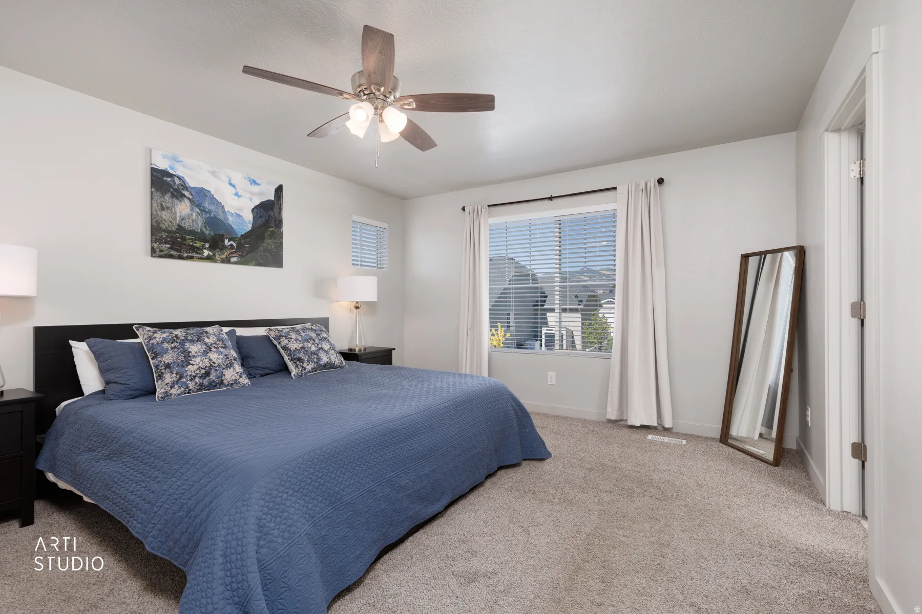 Spacious room featuring neutral carpeting, a ceiling fan with integrated lighting, and a large window with blinds and drapes