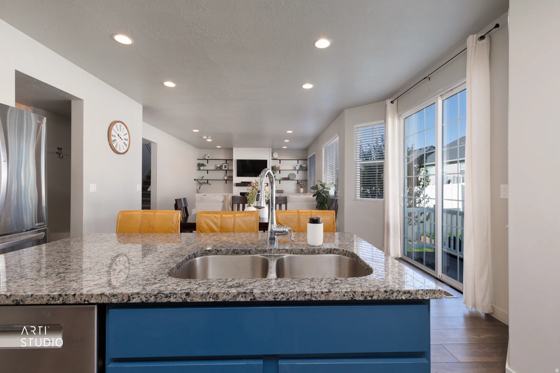 Kitchen island featuring a double basin stainless steel sink, granite countertop, and blue cabinetry