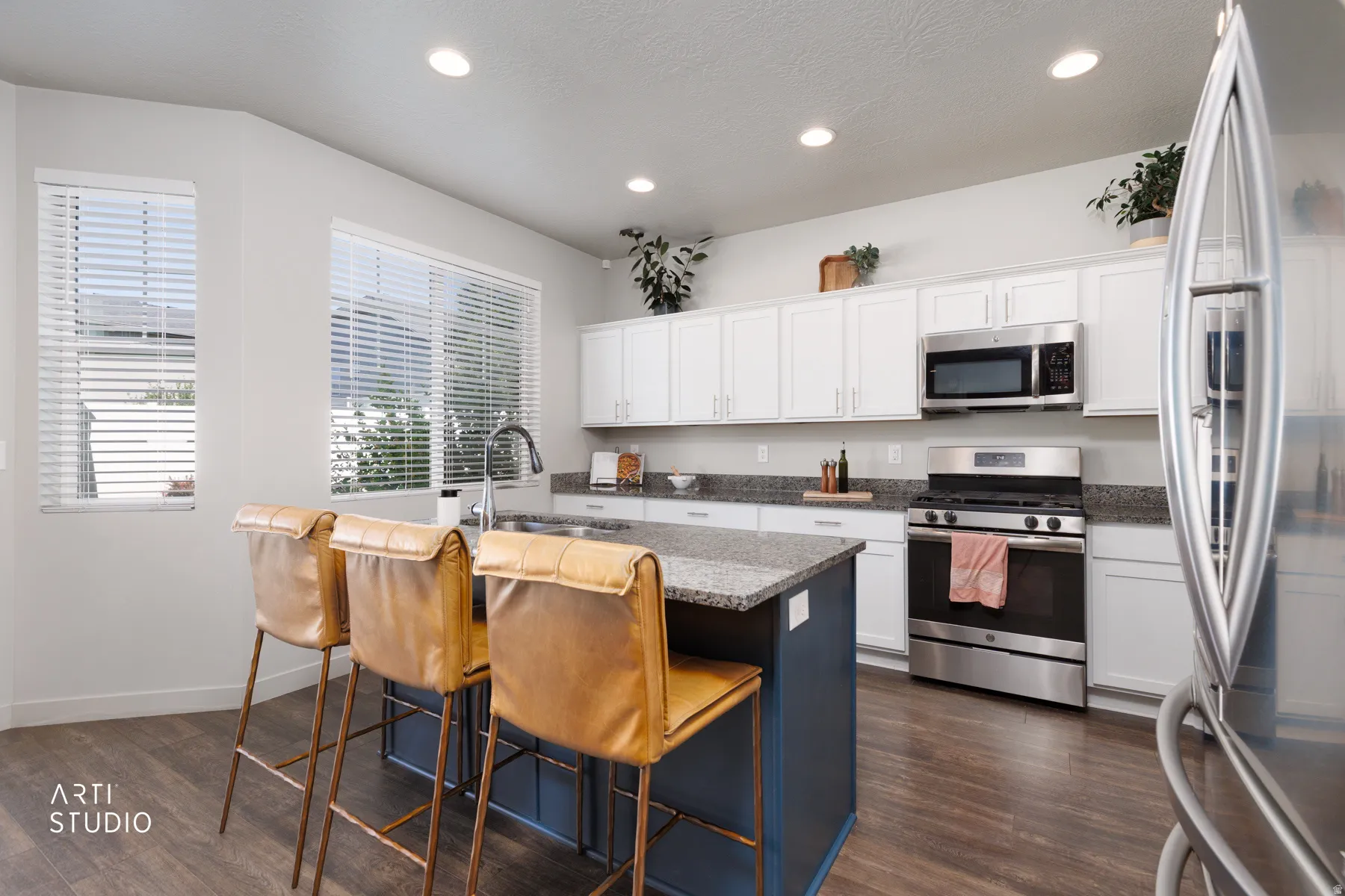 Kitchen featuring a central island with a sink, stainless steel appliances, white cabinetry, and recessed lighting