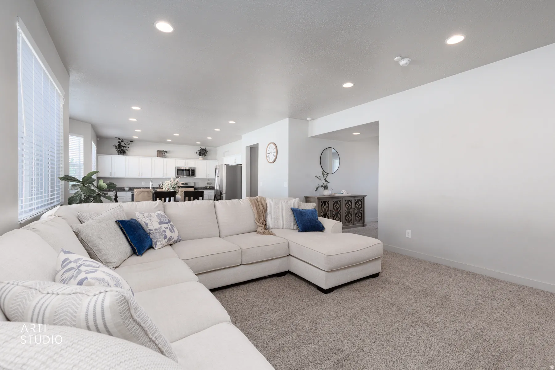 Open-concept living area featuring recessed lighting, light-toned walls, and a carpeted floor