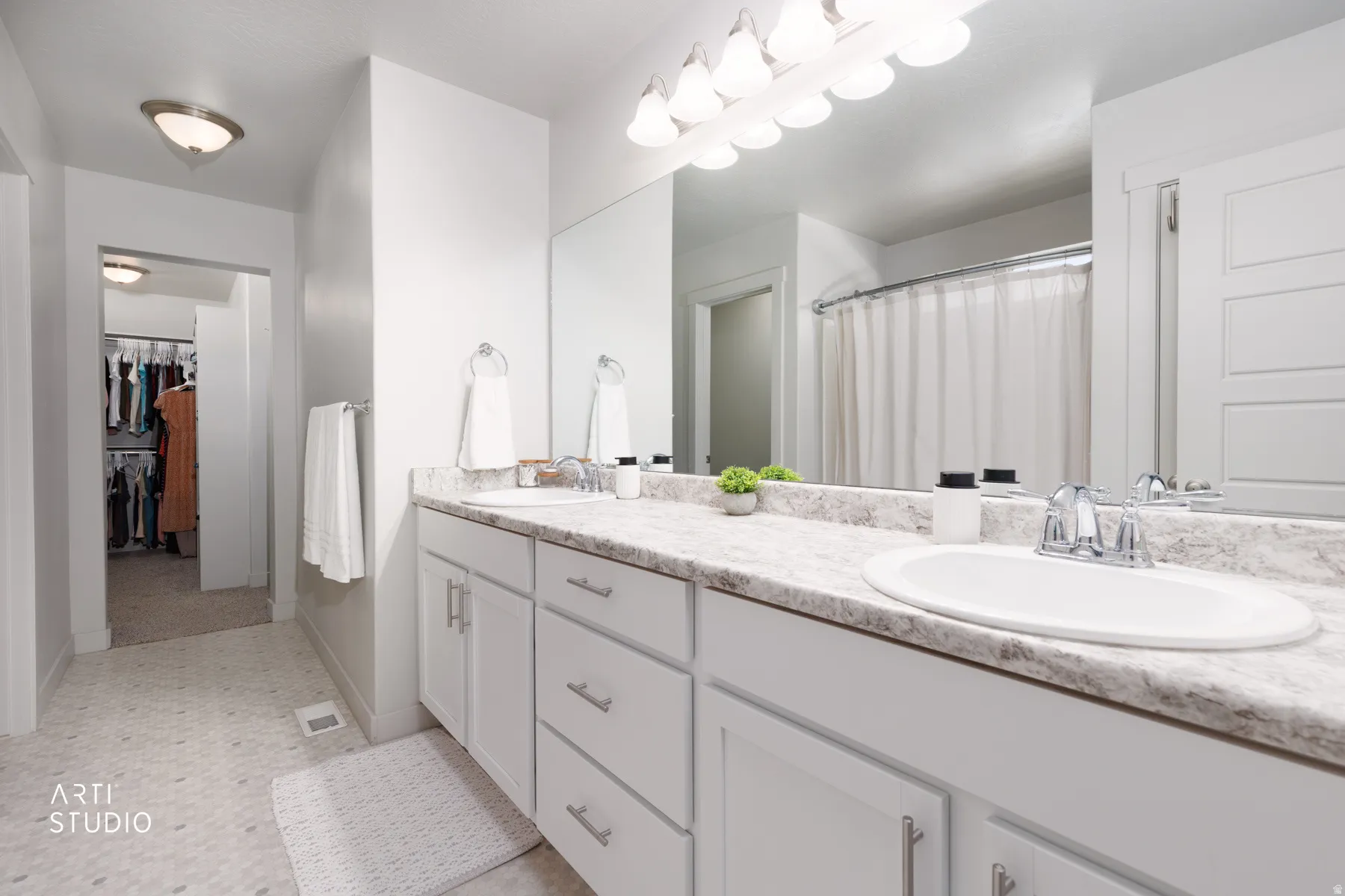 Dual vanity with white cabinetry, integrated sinks, and a stone-finish countertop