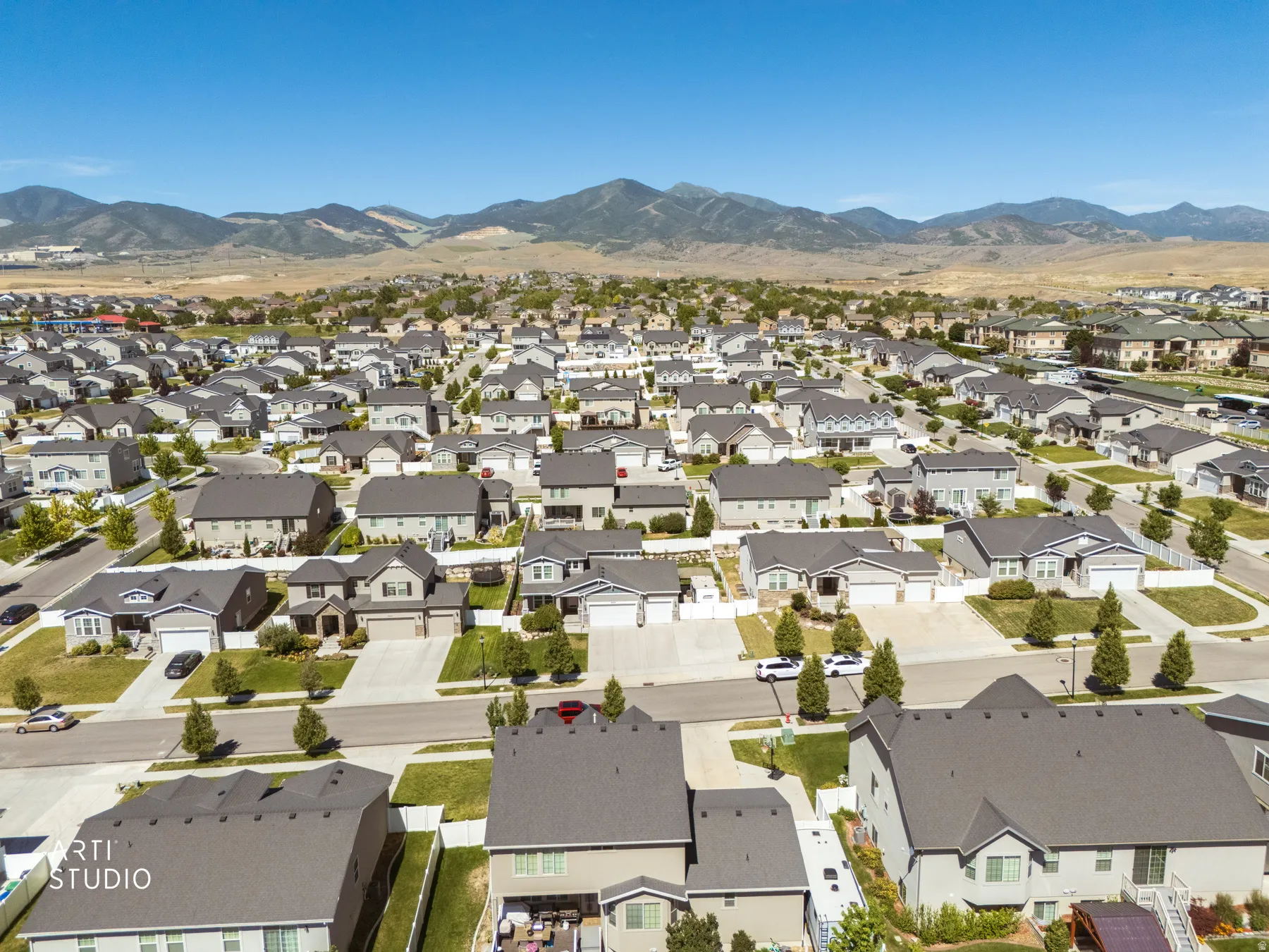 Aerial perspective of a developed residential community featuring numerous single-family homes with dark shingle roofs, individual driveways, and landscaped yards