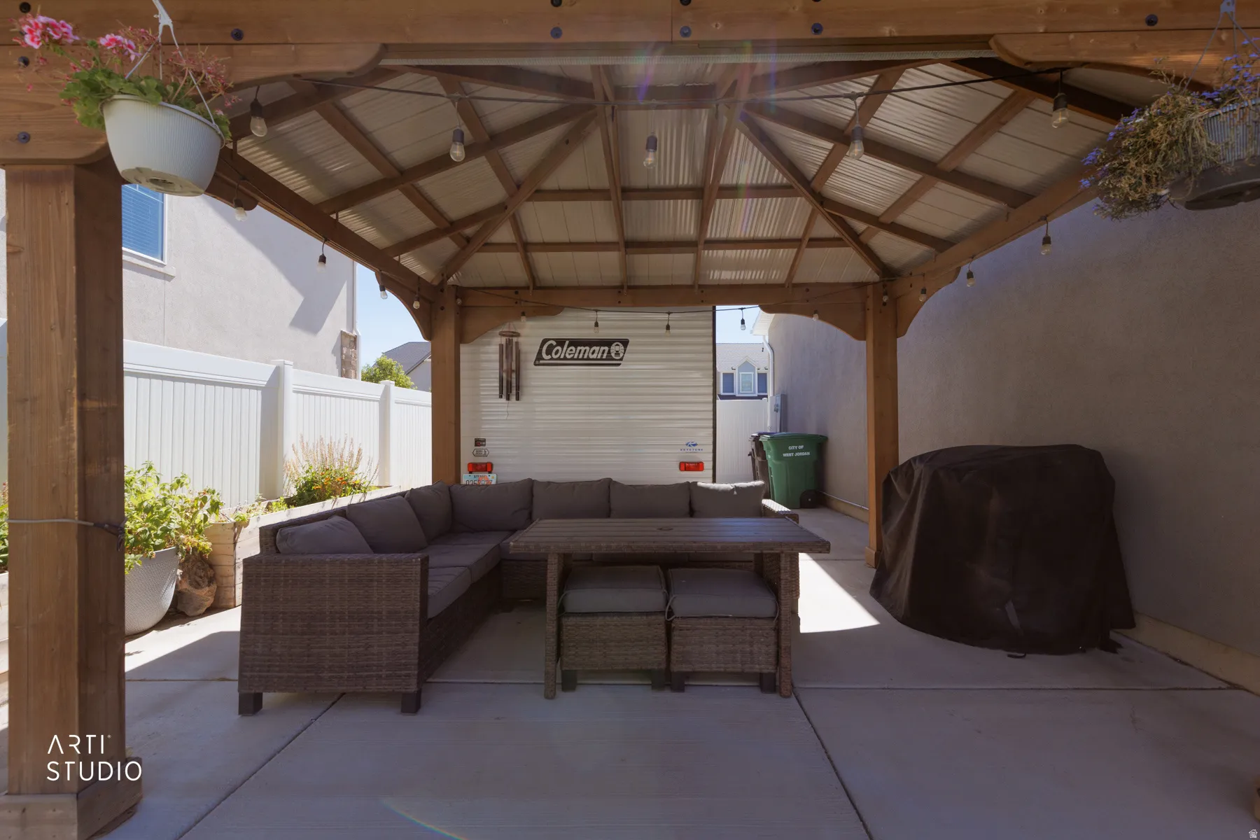 Spacious covered patio area featuring a wooden gazebo with a metal roof, string lighting, and a concrete slab