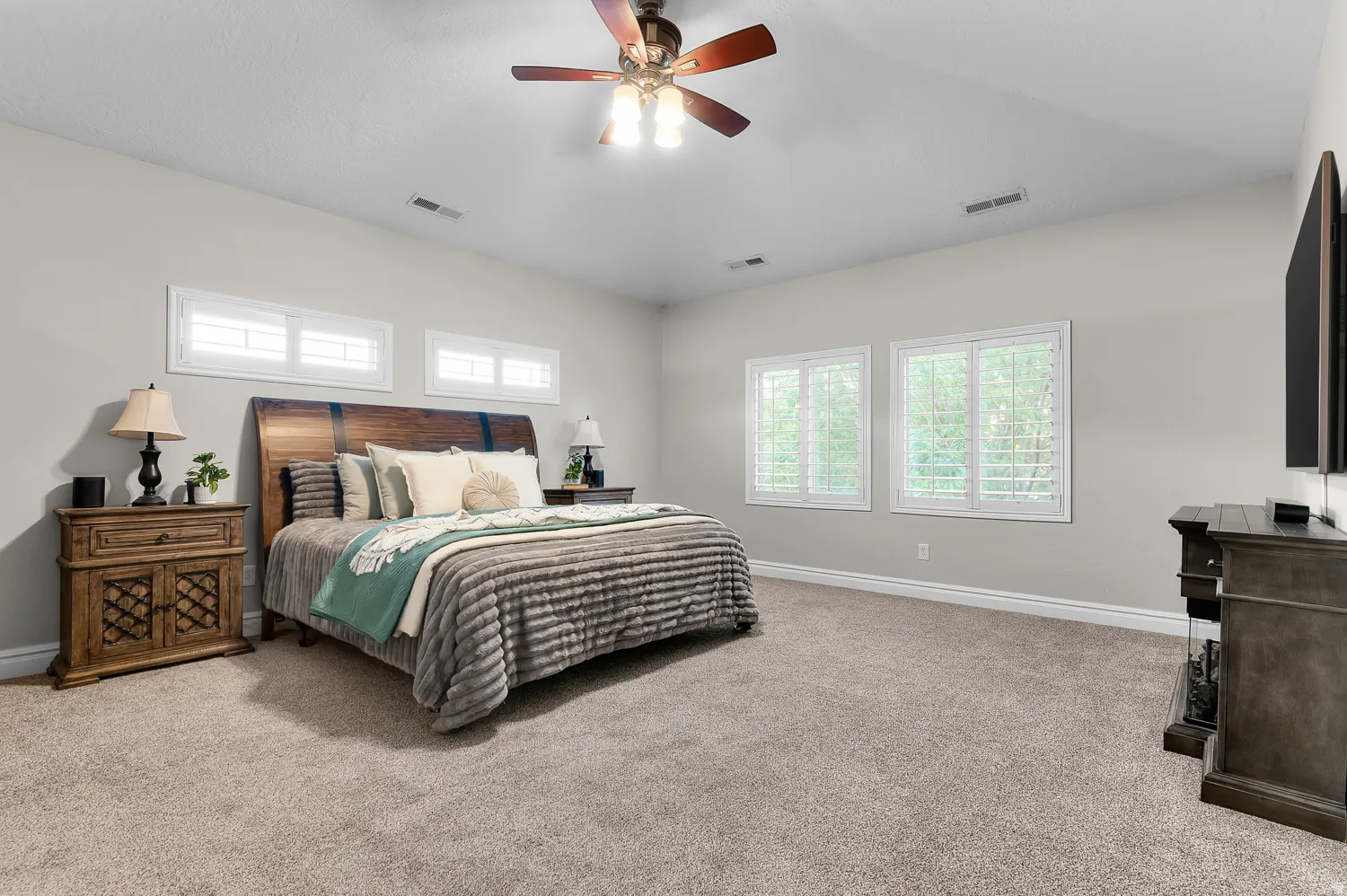 Spacious room featuring neutral carpeting, light-toned walls, and a ceiling fan with integrated lighting