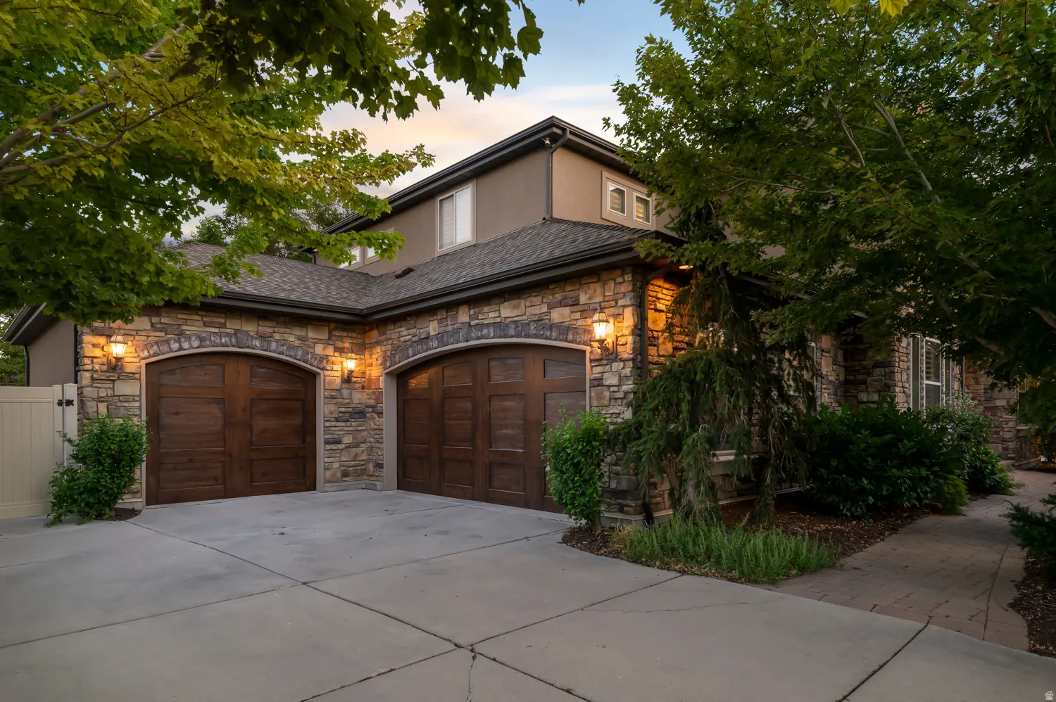 Stone veneer facade with two arched wood-finish garage doors