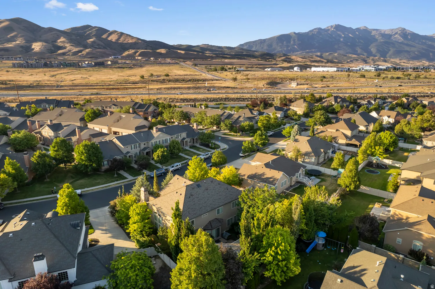 Residential neighborhood featuring mature trees, paved streets, and a mountainous backdrop