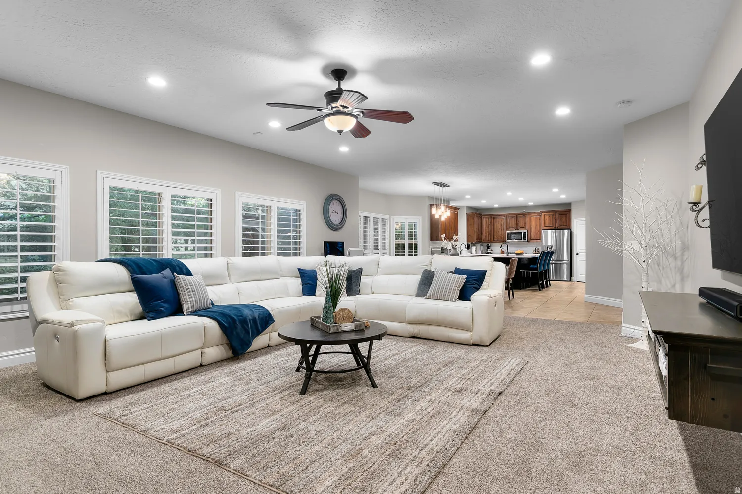 Spacious living area featuring neutral carpeting, recessed lighting, and a ceiling fan
