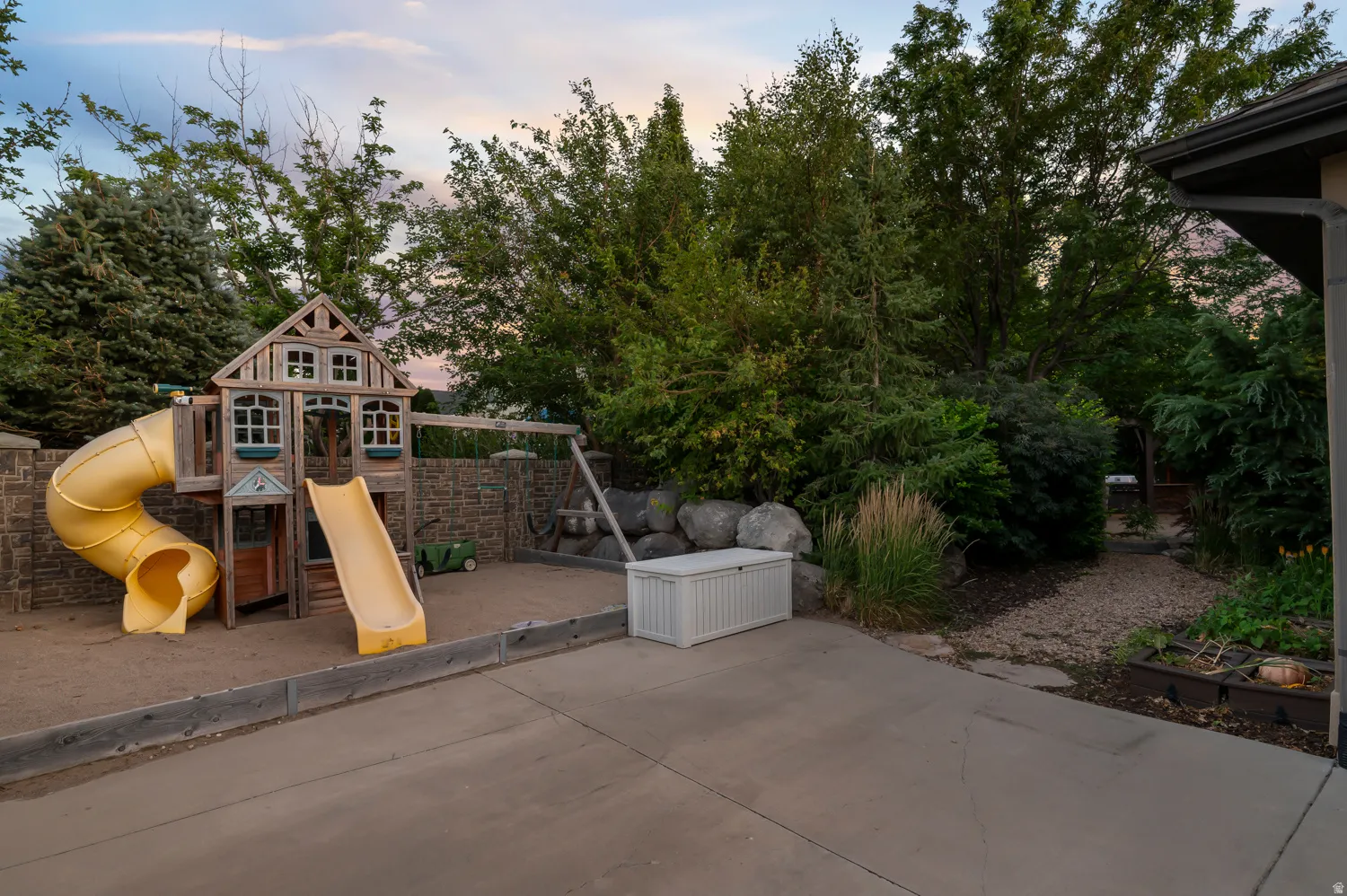 Recreational play structure featuring a straight slide and a spiral slide, set within a sand-covered area