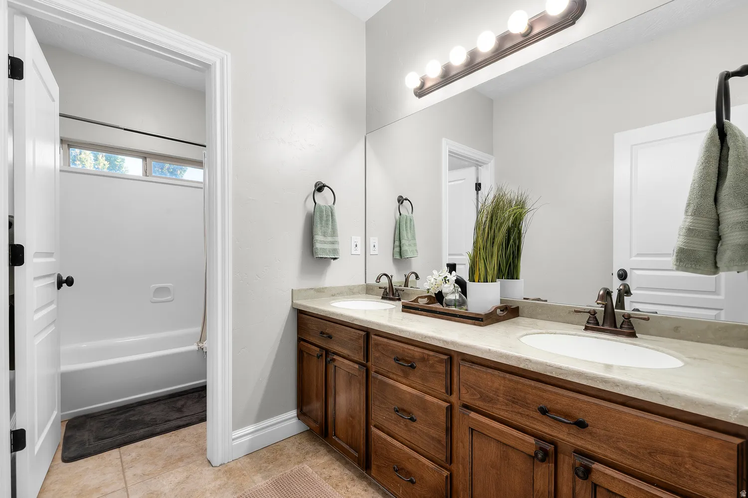 Double vanity featuring wood-finish cabinetry, light-toned countertops, and bronze-finish fixtures