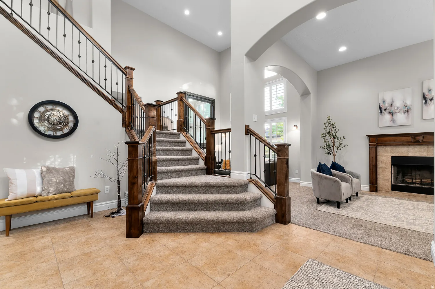Carpeted staircase with rich wood-finish railings and black iron balusters