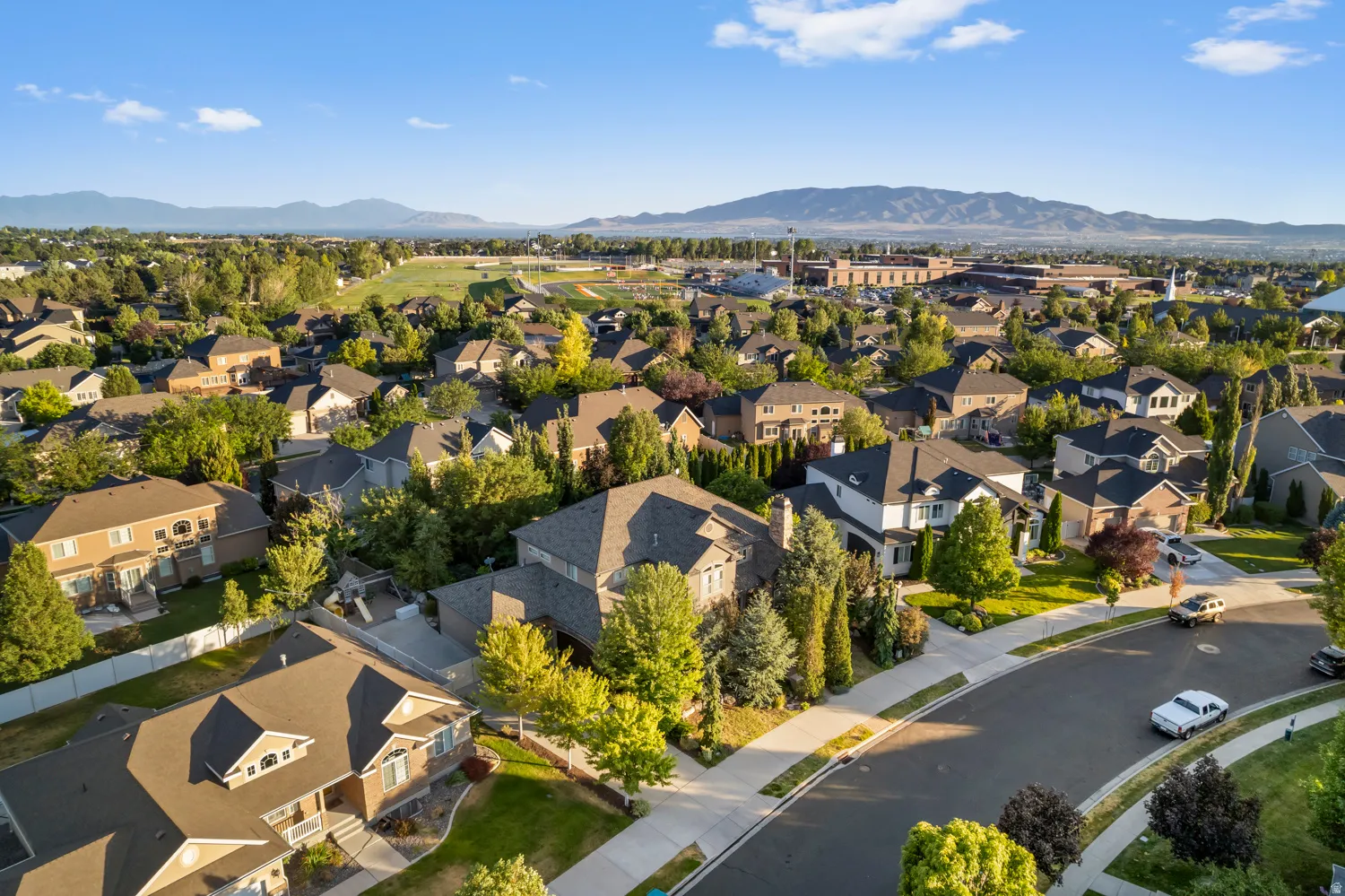 Aerial perspective showcasing a residential neighborhood with mature trees and a curvilinear street layout
