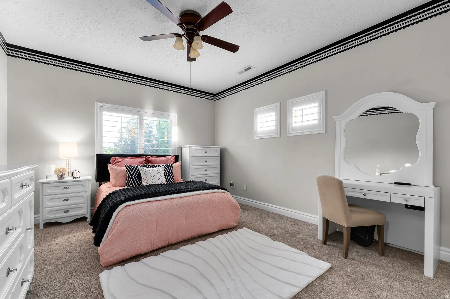 Carpeted room featuring a ceiling fan with integrated lighting, a large window with white plantation shutters, two smaller windows with white plantation shutters, and crown molding details