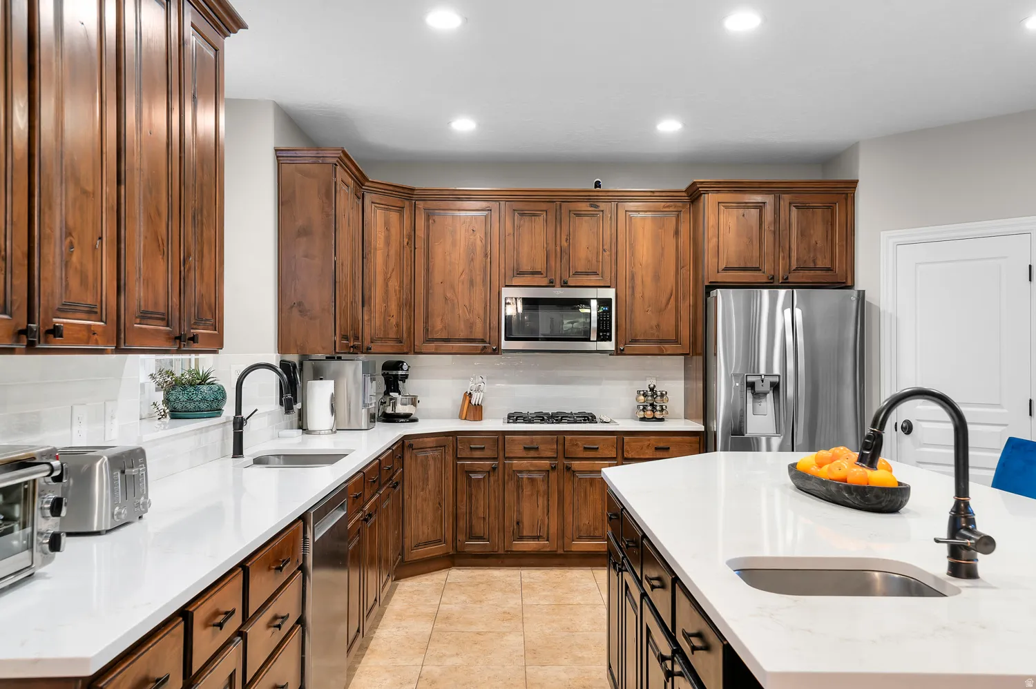 Kitchen featuring wood cabinetry, white countertops, tile flooring, stainless steel appliances, and recessed lighting