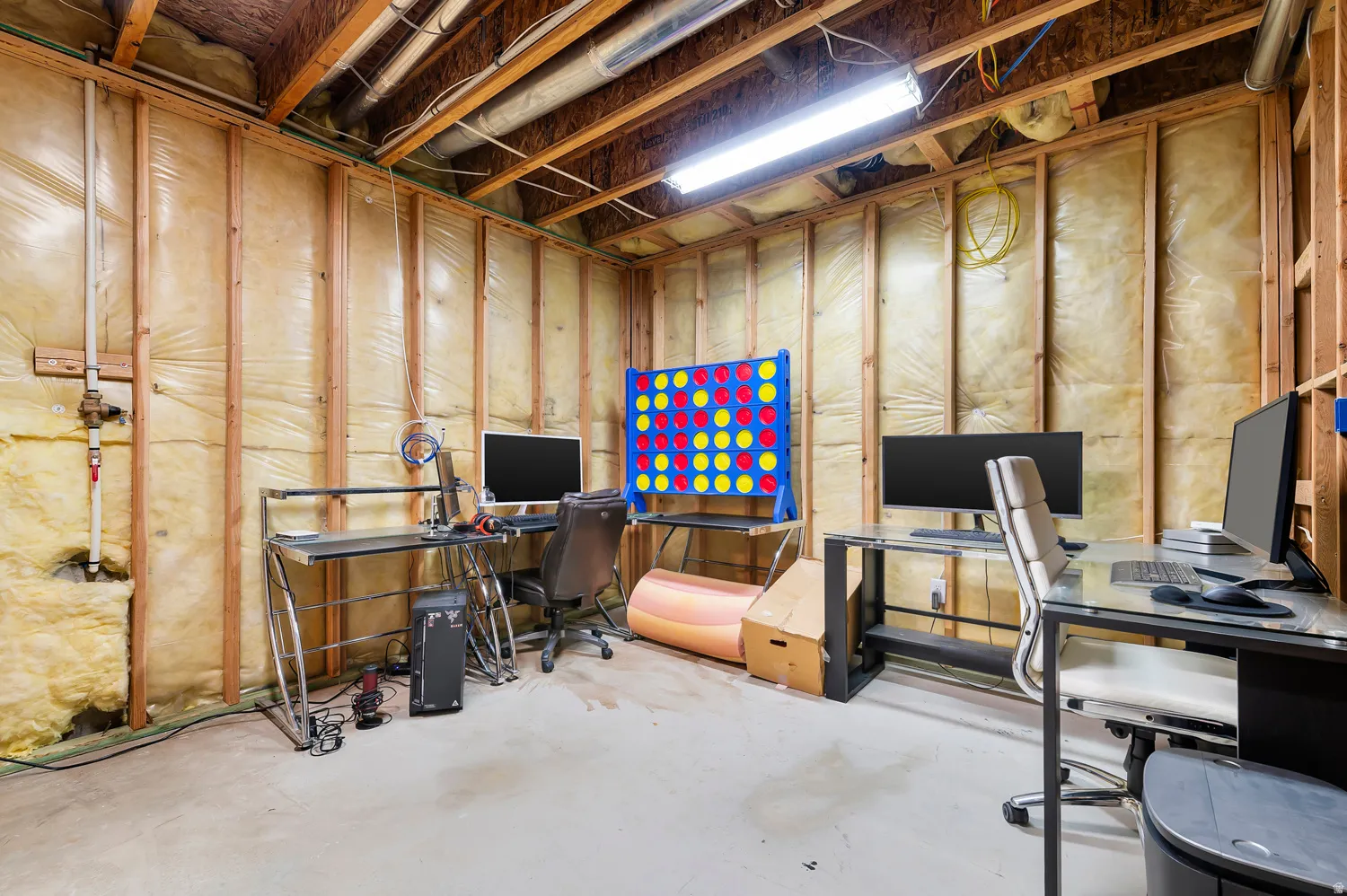 Unfinished basement space featuring exposed wooden studs, insulation, and concrete flooring