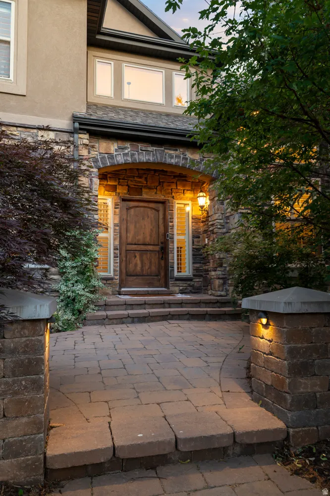 Stone archway entrance featuring a wood-finish door with sidelight windows