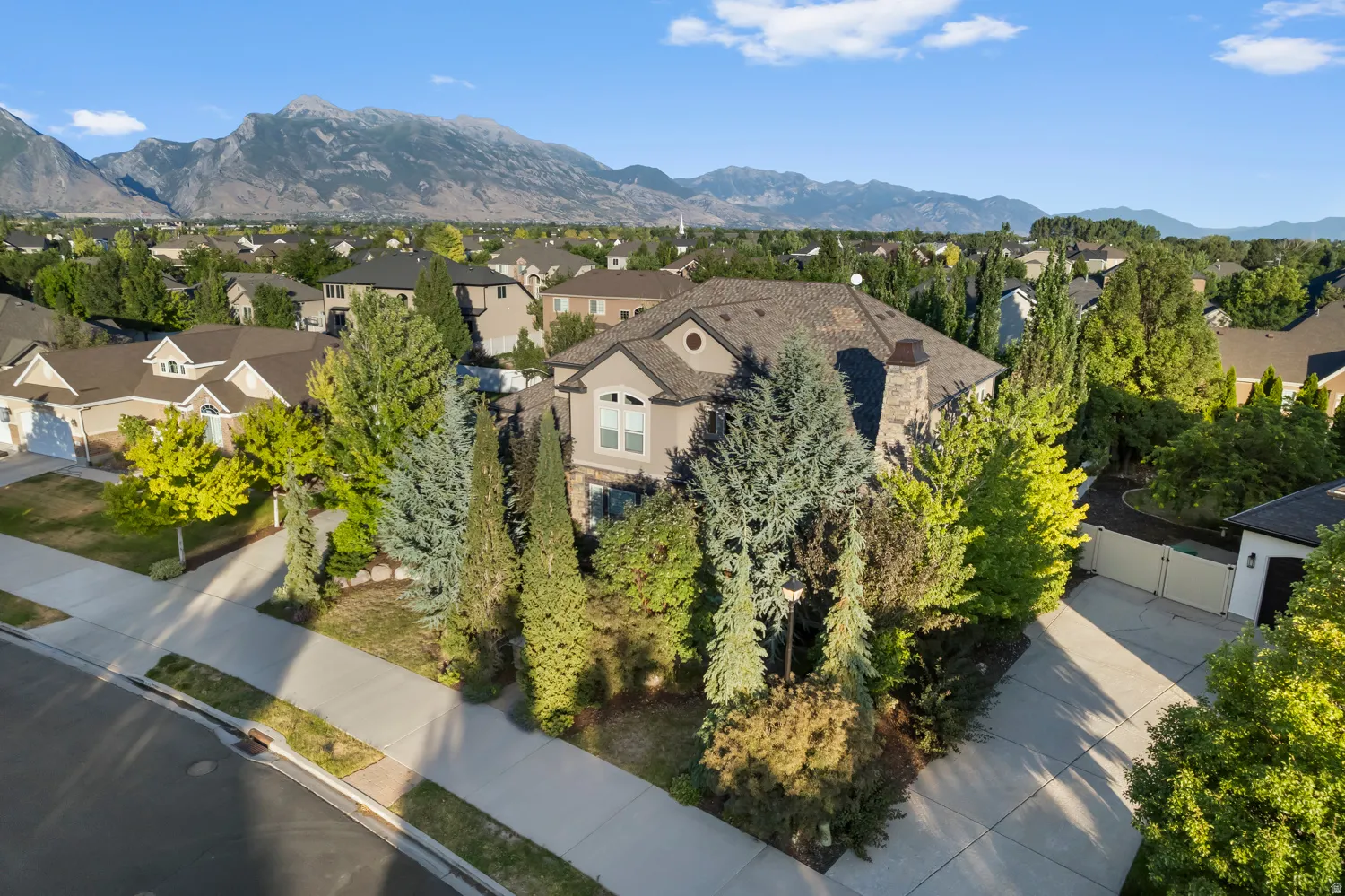 Traditional two-story residence featuring a stone and stucco exterior, prominent bay window, and a dark shingle roof