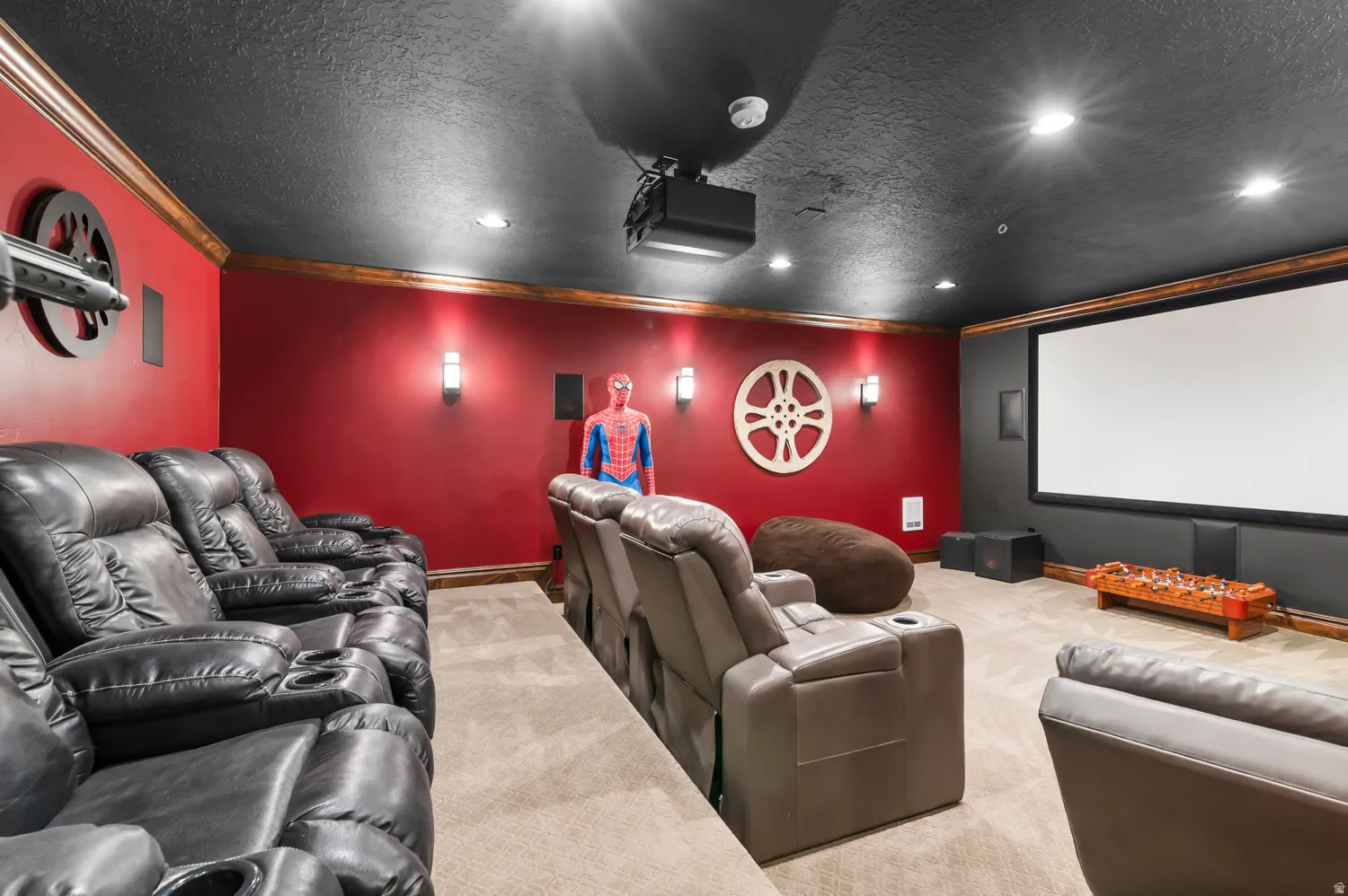 Dedicated media room featuring a large projection screen, recessed lighting, and wall-mounted sconces