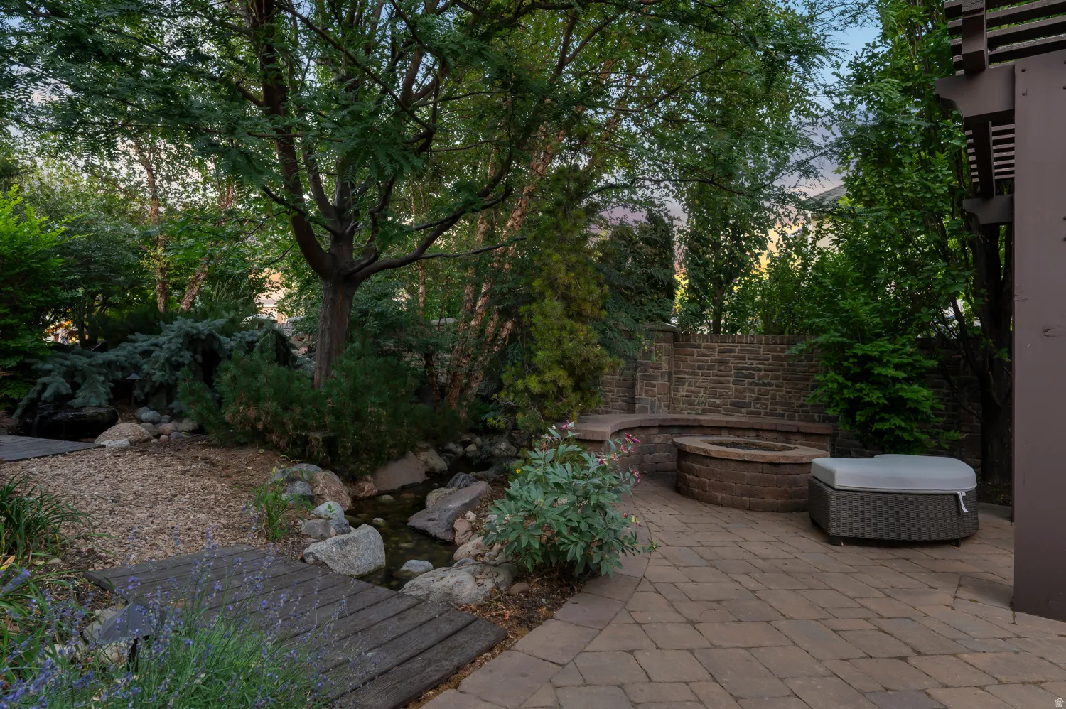 Paver patio with a built-in fire pit, stone seating, and a brick privacy wall