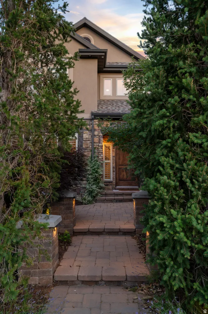 Stucco and stone exterior featuring a gabled roofline, dark trim, and multiple windows