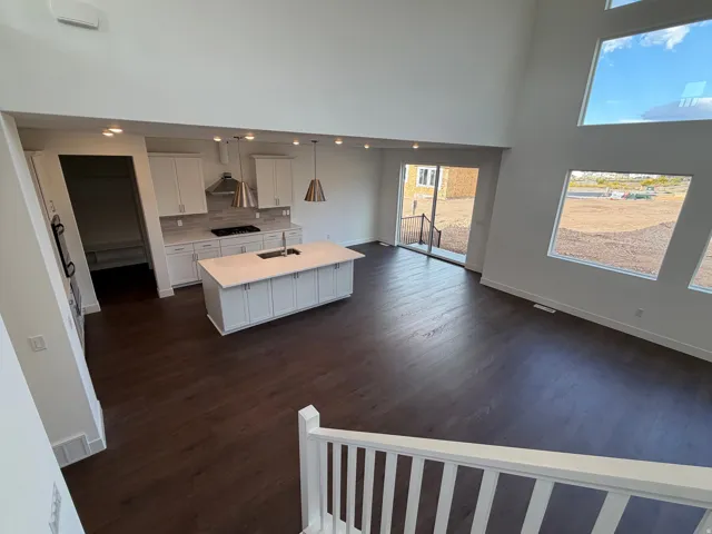 Open-concept living space featuring high ceilings, dark wood-finish flooring, and expansive windows