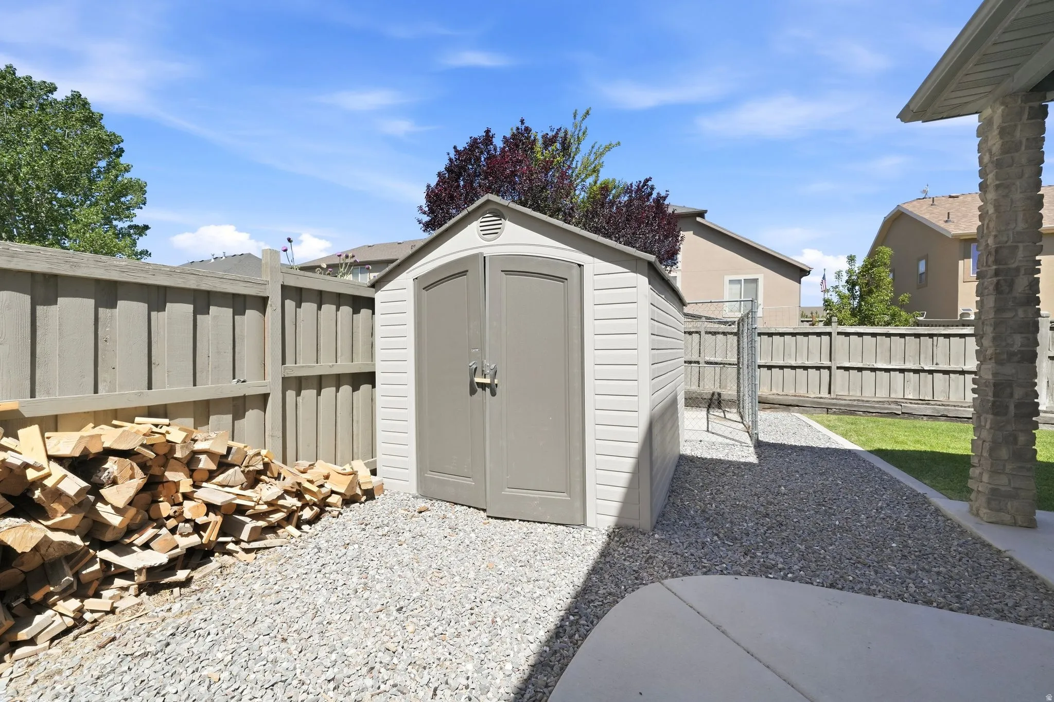 Enclosed outdoor area featuring a storage shed, gravel ground cover, privacy fencing, and a concrete patio section