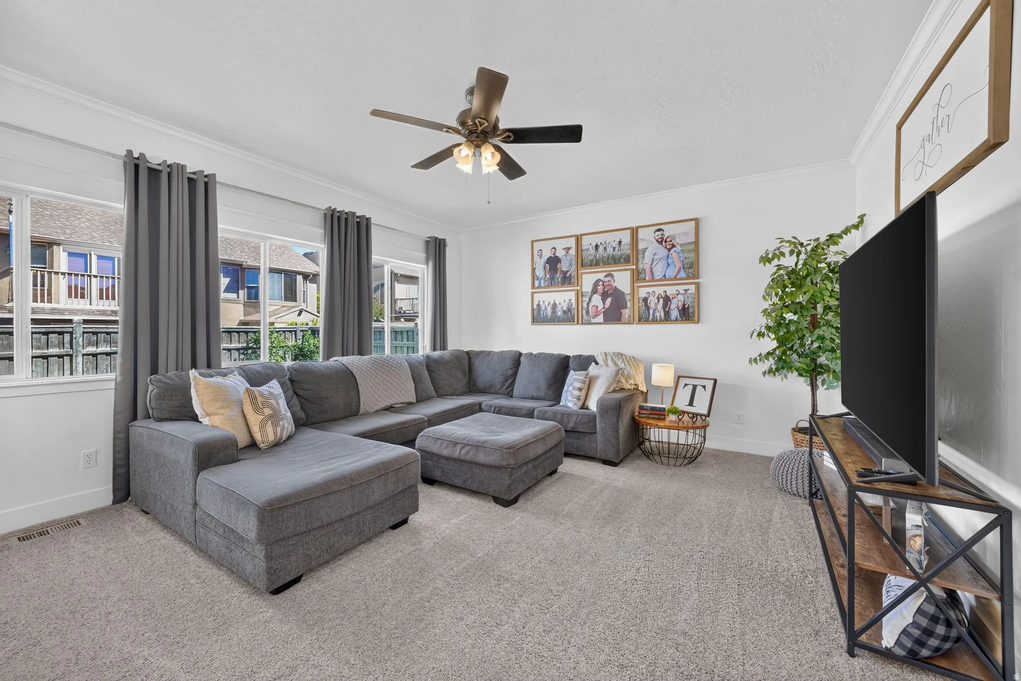Bright living area featuring light gray carpeting, crisp white walls with crown molding, and large windows with white trim