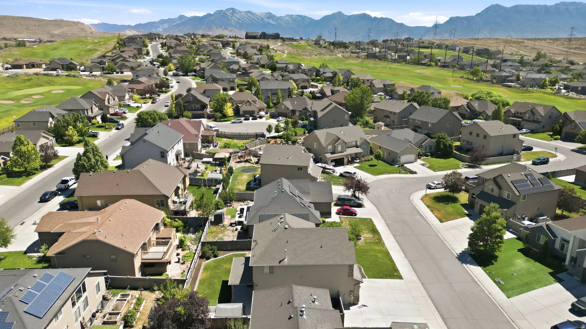 Residential neighborhood featuring various architectural styles, paved streets, and green spaces, with distant mountains forming a scenic backdrop