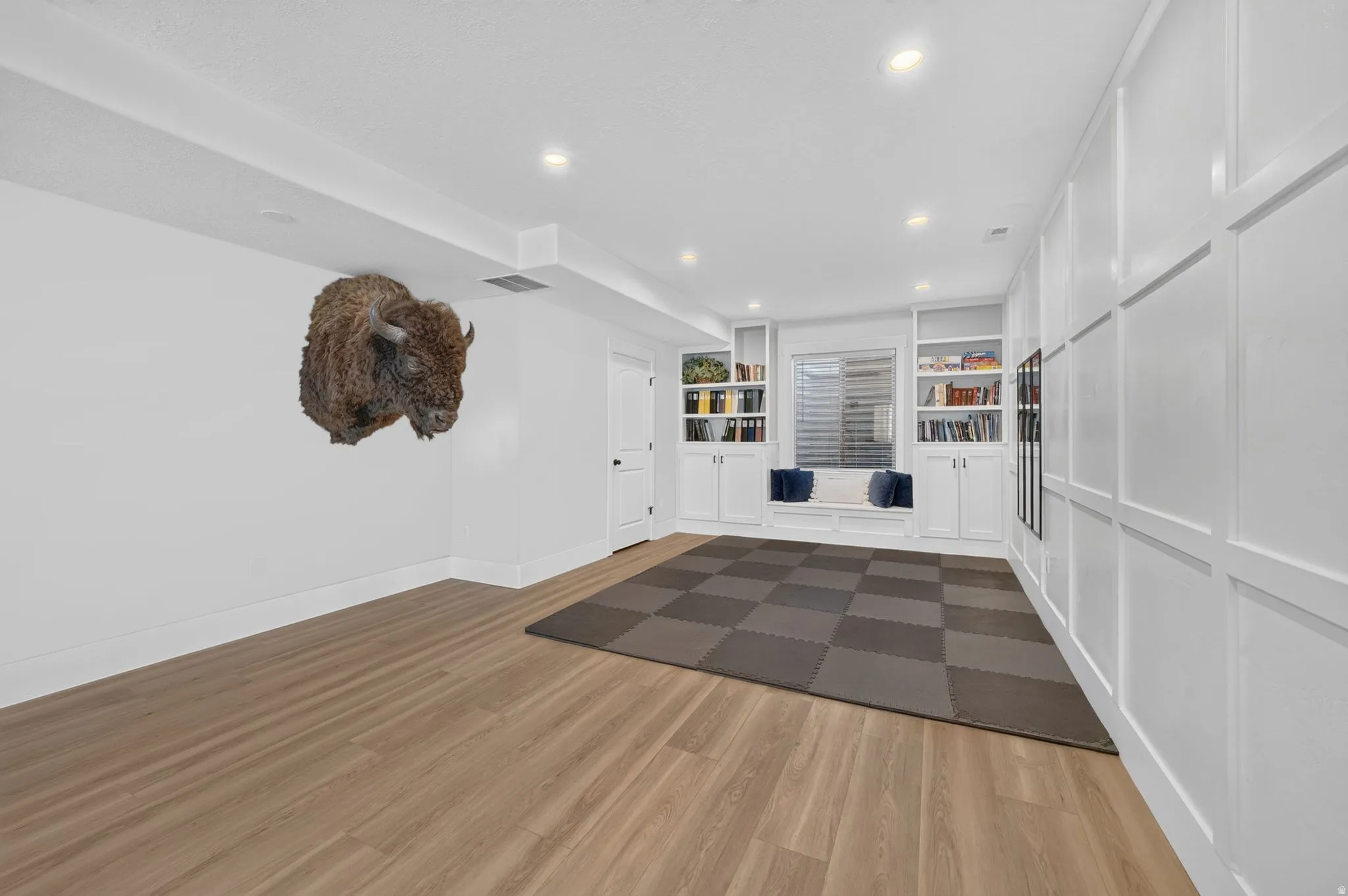 Spacious room featuring light wood-finish flooring, recessed lighting, and a window seat with built-in cabinetry