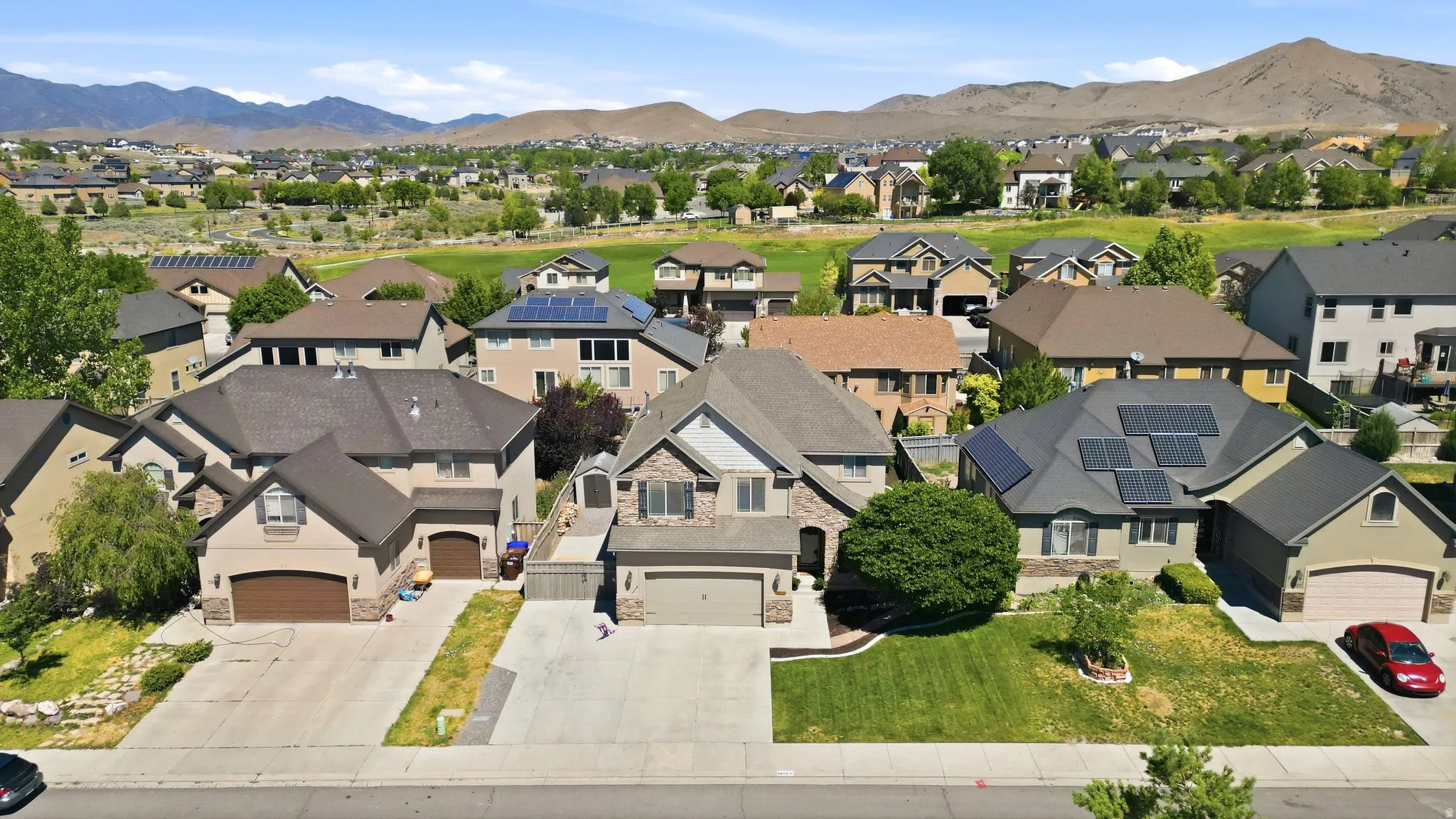 Residential street featuring two-story homes with attached garages, paved driveways, and landscaped front yards